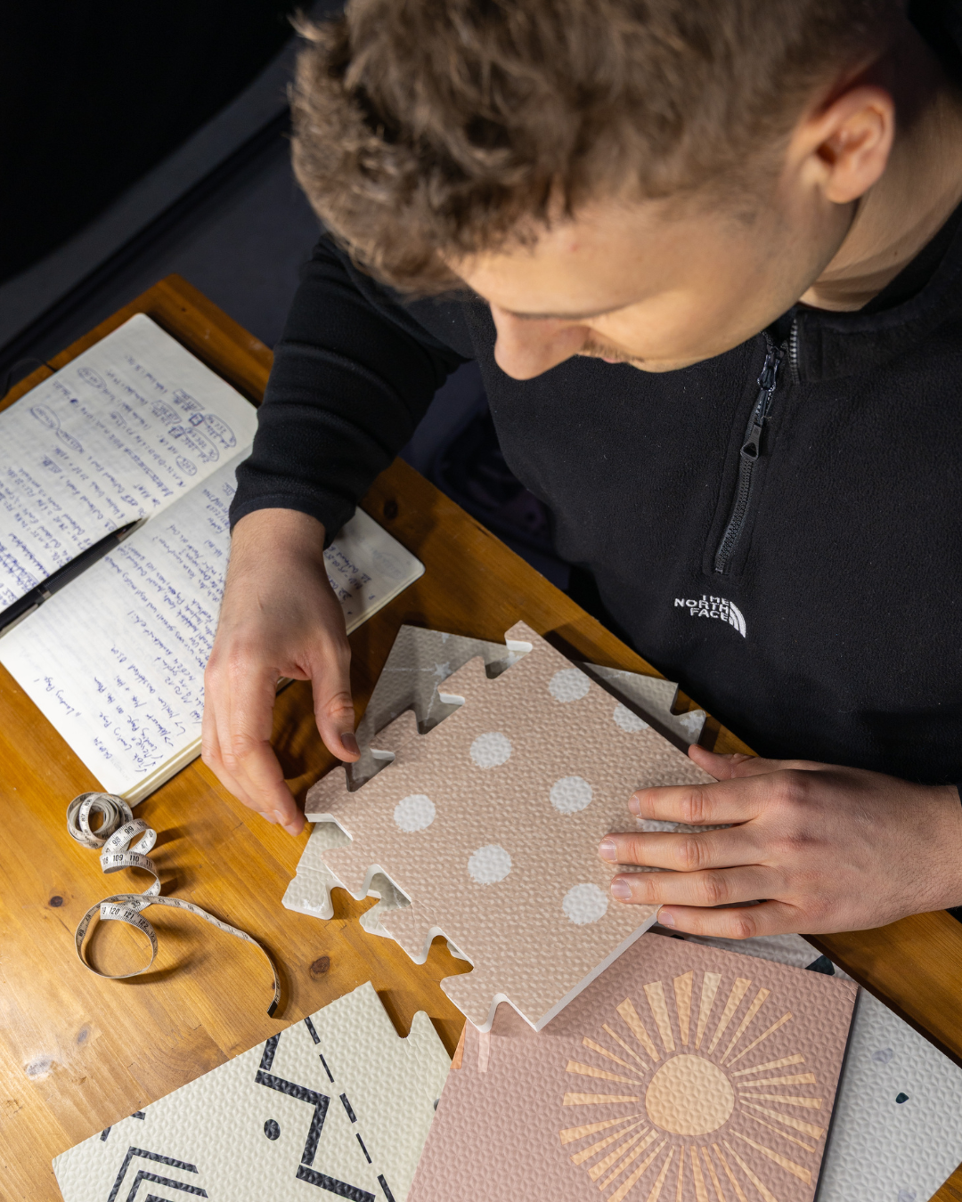 Produktdesigner prüft verschiedene Puzzlematten mit kinderfreundlichen Mustern – Vorbereitung für neue Babyspielmatte bei Jolovi